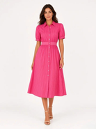 A woman modeling a bright pink midi shirt dress with vertical pinstripes, short puff sleeves, a button-down front, and a matching pink belt, photographed against a plain white studio background.