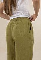 Person wearing green pants with a pocket detail on a beige background