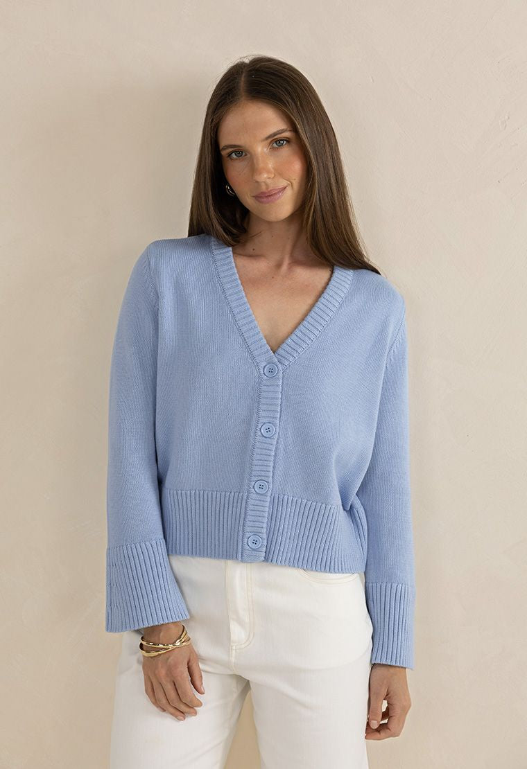 Woman wearing a light blue cardigan against a beige background