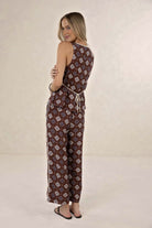 Woman wearing a patterned jumpsuit on a plain background
