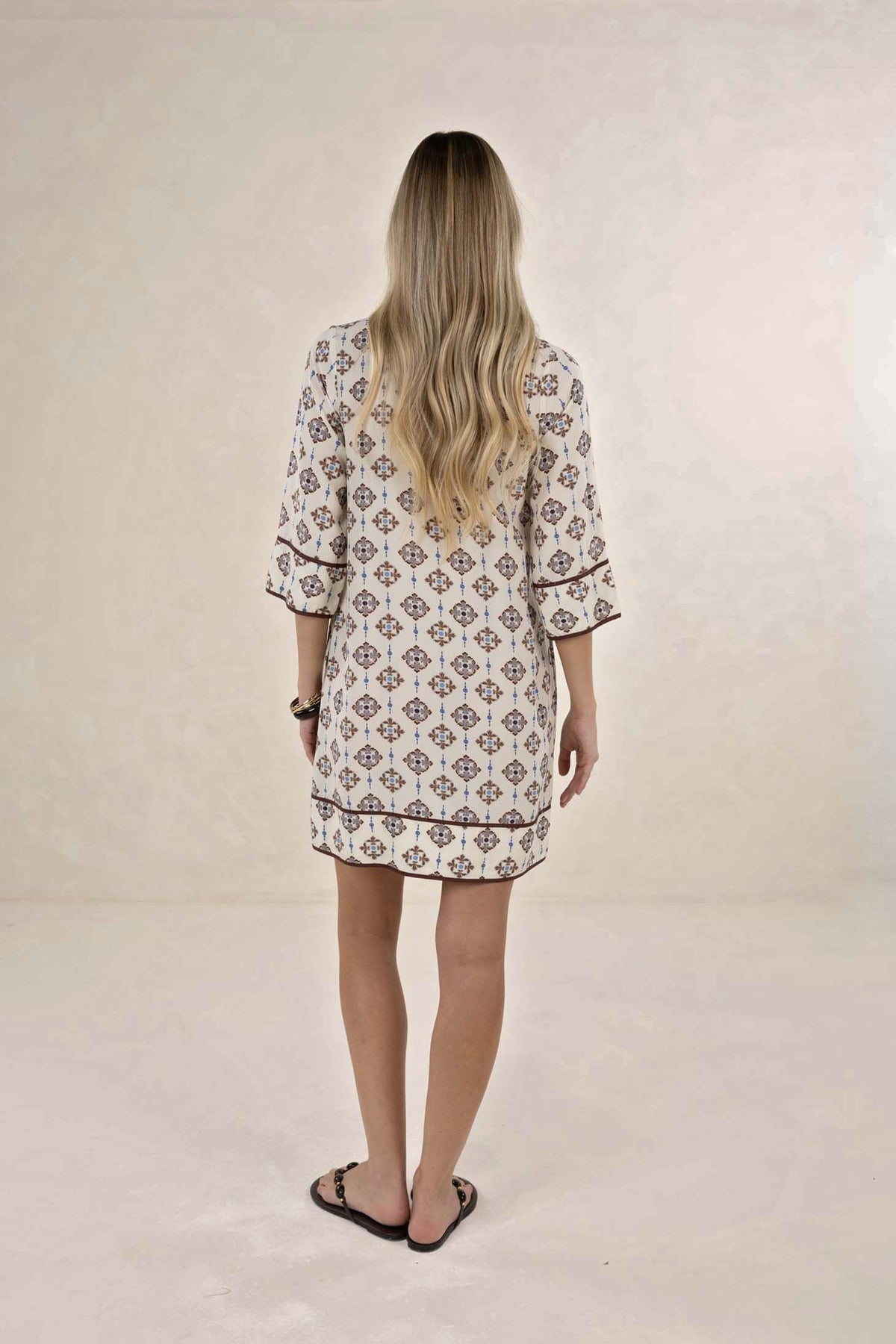 Woman wearing a patterned dress on a plain background