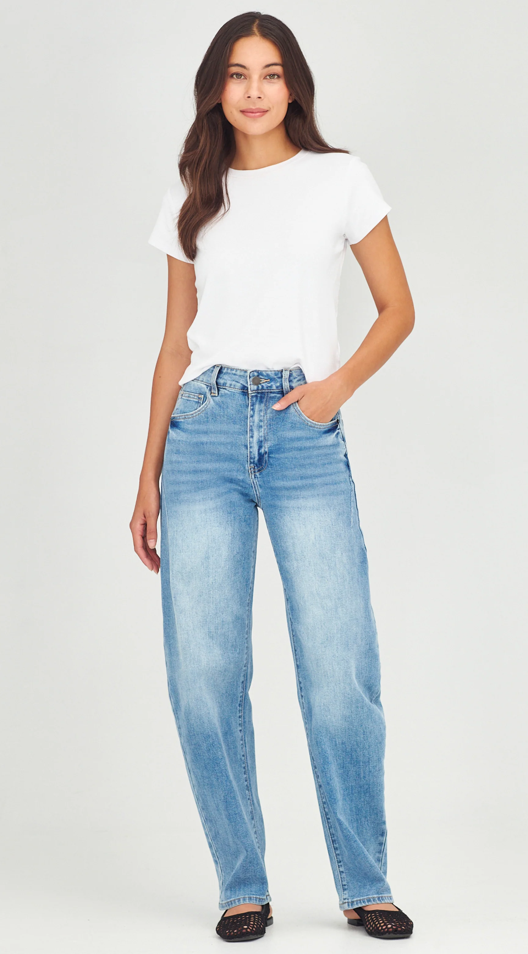 Woman wearing a white t-shirt and blue jeans on a plain background