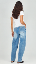 Person wearing light blue jeans and a white t-shirt on a plain background