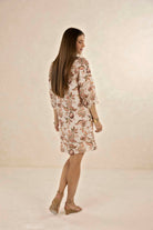 Woman wearing a floral dress against a plain background