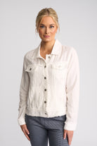A woman modeling a light cream/off-white denim jacket with a raw, frayed hem and cuffs, paired with gray pants, against a solid light gray background.