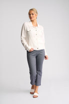 A woman modeling a white button-up shirt and gray cropped pants against a light gray studio background.