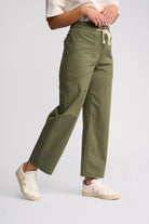 A person wearing olive green wide-leg cropped pants with a white drawstring waist, paired with white sneakers, shown against a light gray studio background.