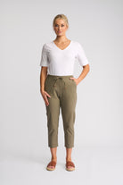 A woman modeling a white short-sleeve V-neck t-shirt and olive green cropped drawstring pants, paired with brown slide sandals, against a light gray studio background.
