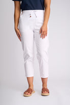 White cropped drawstring pants worn by a model, paired with a navy top and brown slide sandals, photographed against a light gray studio background.