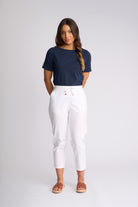 A woman modeling a navy blue short-sleeve crewneck t-shirt and white cropped drawstring pants, paired with brown slide sandals, against a light gray studio background.