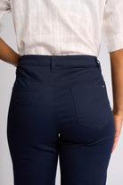 Close-up back view of a person wearing dark navy blue pants with a white patterned short-sleeve top, showing the back pockets and waistband details.